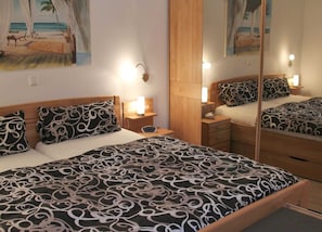 A hotel room with a bed, bedside tables, lamps, and a large mirror reflecting the room.
