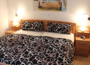 A bed with a patterned bedspread, two bedside tables with lamps, and a painting on the wall.