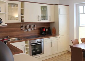 A kitchen with white cabinets, a stainless steel oven, a coffee maker, and a wooden countertop.