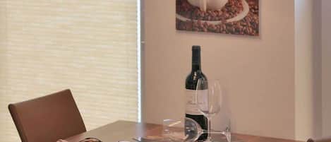 Een eettafel met een fles wijn, twee wijnglazen en een decoratieve schaal.