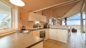 Een moderne keuken met houten kastjes, een ingebouwde oven en een groot raam met uitzicht op de omgeving.