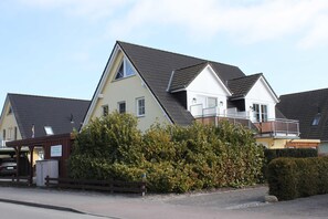 A row of two-story houses with sloped roofs, a covered parking area, and a well-maintained hedge. - Apartment Sanddorn - Apartment Sanddorn-1 bedroom for max. 4 persons and 1 baby (Karlshagen)