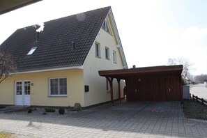 Uma casa de dois andares com um caminho de entrada com tijolos e uma varanda coberta.