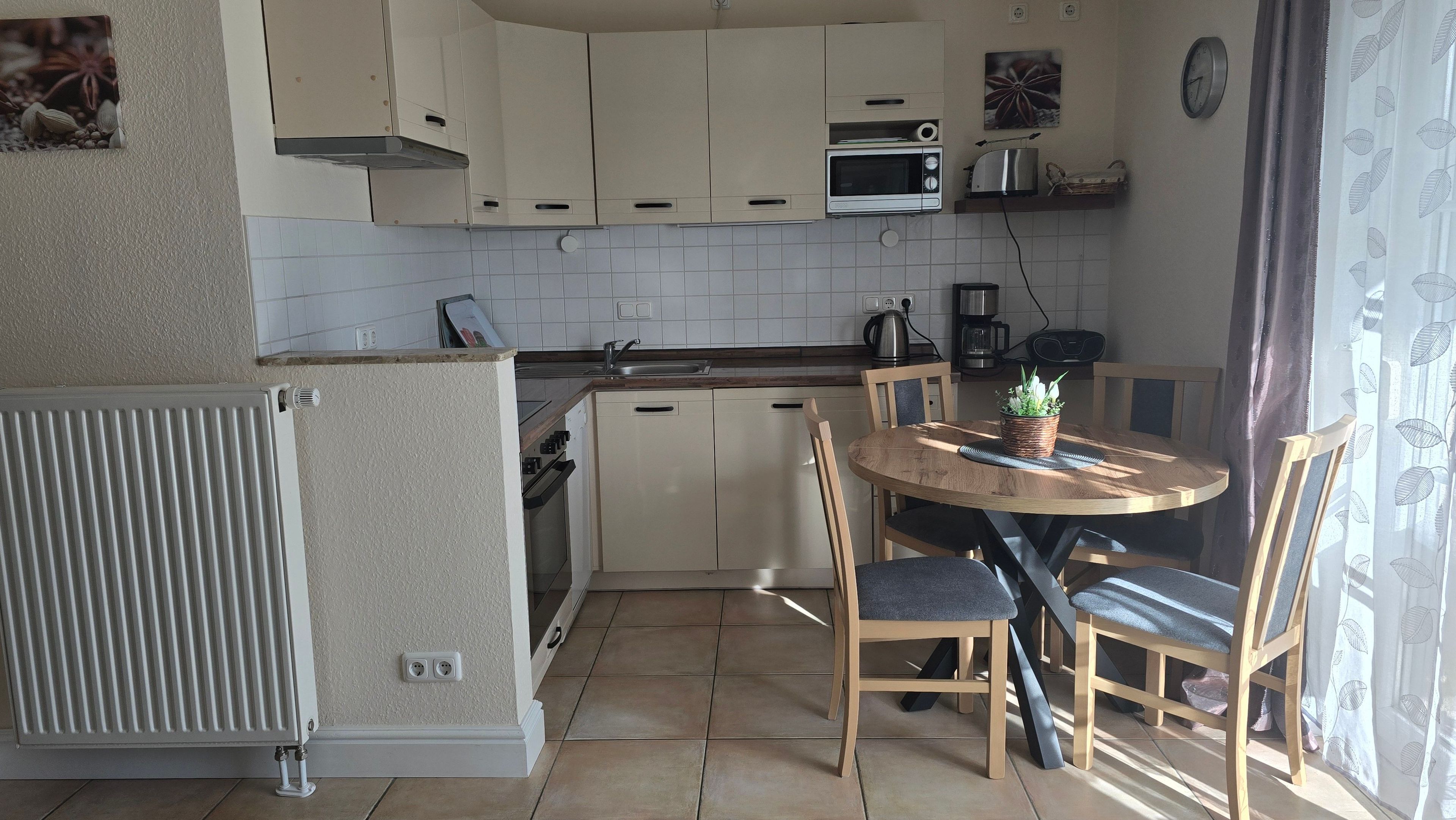 Una cocina con una mesa de comedor, sillas, un radiador y un reloj en la pared.