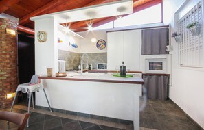Eine moderne Küche mit Kochinsel, Mikrowelle, Herd und kleinem Backofen.