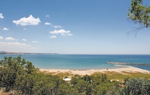 Een kustlandschap met een strand, een pier en een heldere lucht.