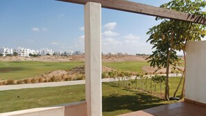 A balcony with a view of a golf course and residential buildings. - Amazing apartment in Roldán with swimming pool (Roldán)