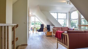 Un loft spacieux avec un plafond haut, de grandes fenêtres, un plancher en bois, un canapé rouge, une télévision et un coin repas.