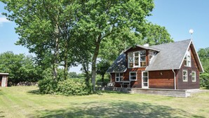 Une maison en bois à deux étages, dotée d’un toit en pente, de grandes fenêtres et d’une antenne parabolique sur le toit.