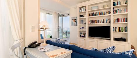 Una sala de estar con un sofá azul, un televisor de pantalla plana y una estantería llena de libros.