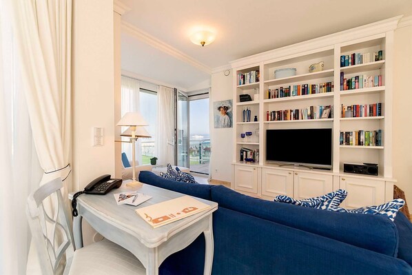 A living room with a blue sofa, a flat-screen TV, and a bookshelf filled with books.