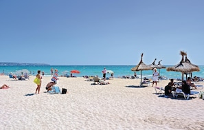 Ein Strand mit Liegestühlen, Sonnenschirmen und entspannten Menschen.