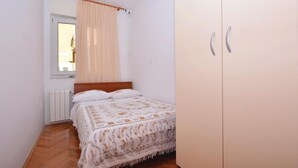 A bedroom with a bed, a wardrobe, and a window with curtains. - Amazing apartment in Omis with WiFi (Omis)