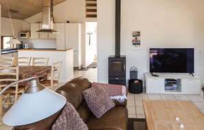 Uma sala de estar moderna com sofá, televisão e lareira a lenha.