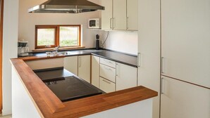 Una cucina moderna con piano di lavoro in legno, cappa in acciaio inossidabile, mobili bianchi e forno a microonde integrato.