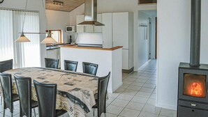 Una cucina moderna con un'isola centrale, un'area pranzo con tavolo e sedie, e un camino a legna.