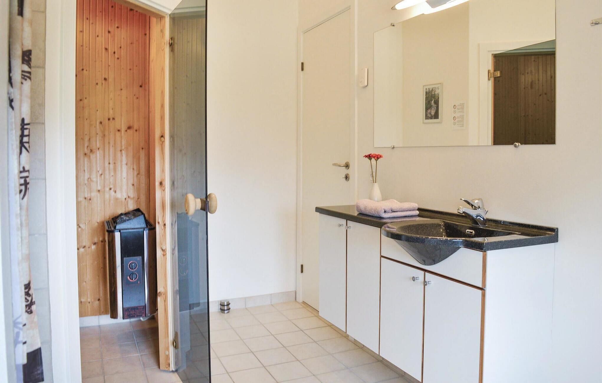 A bathroom with a black sink, white cabinets, a wooden door, and a mirror.