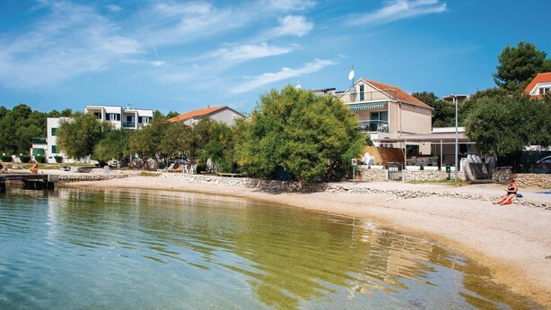 A beachside hotel with clear waters, a sandy shore, and a stone wall. - Amazing apartment in Grebastica (Grebastica)