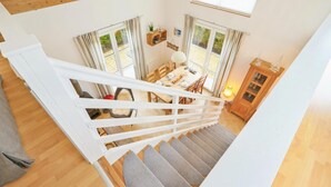 En trappa leder upp till ett matområde med ett bord dukat för fyra personer, ett träskåp och ett fönster med gardiner.