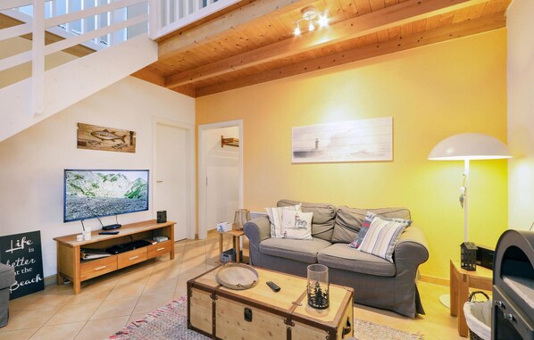 A cozy living room with a wooden ceiling, a television, a sofa, and a lamp.