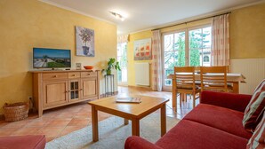 Un salon comprenant un canapé, une table en bois, un téléviseur et un coin repas avec une table et des chaises.