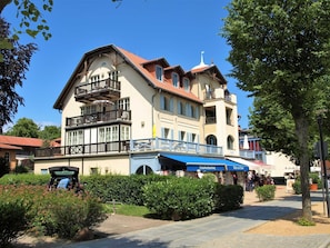 Een gebouw met twee verdiepingen, een balkon, een overdekte doorgang en een bord voor een restaurant.