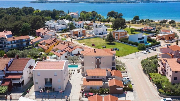 Ein Küstenwohngebiet mit Gebäuden, einer Straße und Blick auf das Meer.