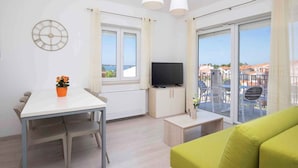 Ein modernes Wohnzimmer mit Essbereich, Fernseher und Balkon mit Blick.