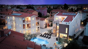 Ein mehrstöckiges Hotel mit Schwimmbad, Balkonen und Innenhof.