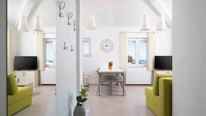 Ein modernes Wohnzimmer mit Essbereich, Fernseher und Blick ins Freie.
