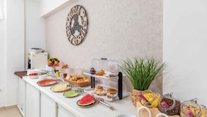 Ein Frühstücksbuffet mit verschiedenen Speisen und einer dekorativen Wanduhr.