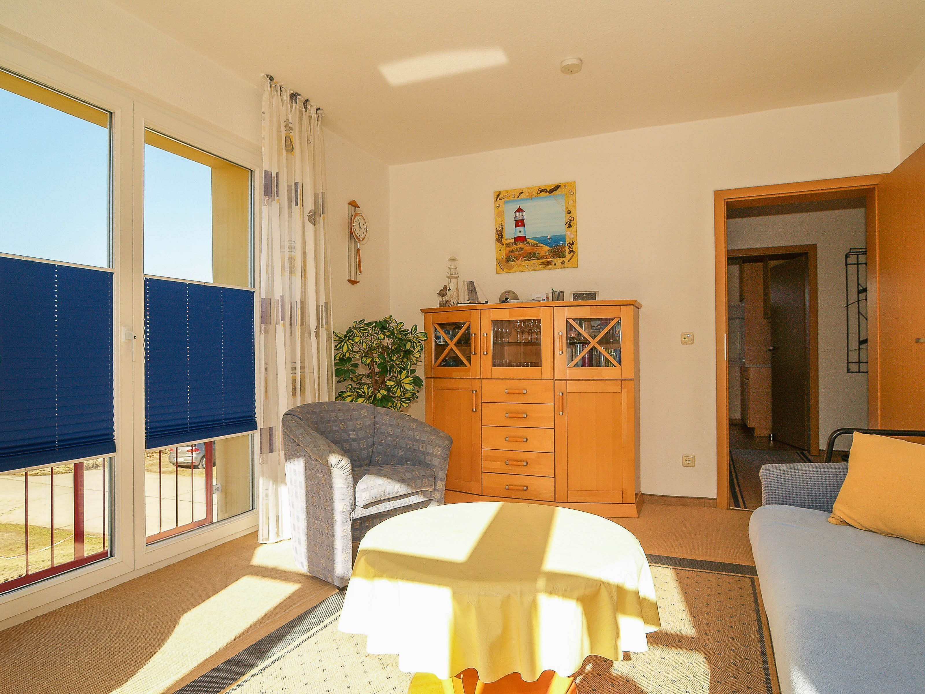 A room with a bed, a chair, a wooden cabinet, and a window with blinds.