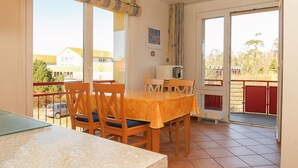 A dining area with a table and chairs, a window with a view of buildings, and a door leading outside. - Dune garden Whg. Wa47-24 - Wa47-24 (Kühlungsborn)