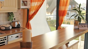 Una cocina con encimera de madera, microondas y hervidor.