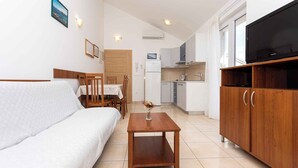 A compact living space with a sofa, dining table, wooden cabinet, and a television.