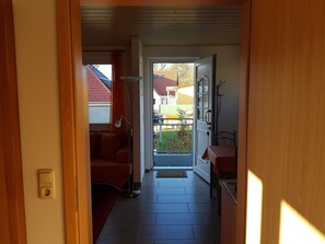 A hallway leading to a balcony with a red chair, a table, and a door. - Room Letting Frank Lemke - Ahlbeck - Holiday House (Heringsdorf)