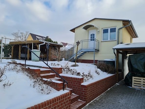 A two-story house with a brick staircase leading to a balcony, a covered porch, and a garage.