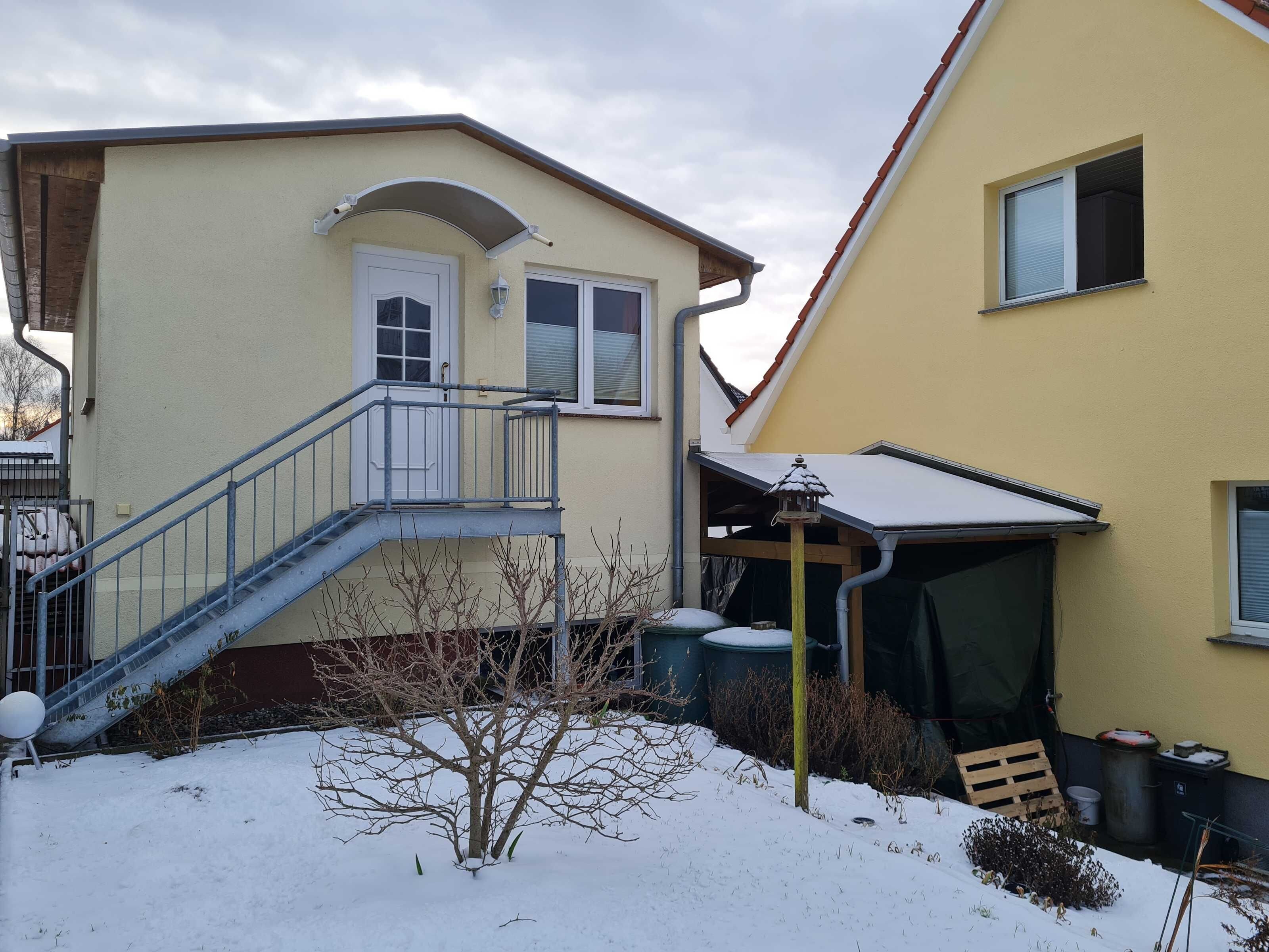 Una casa de dos pisos con una escalera visible, una puerta y una ventana.