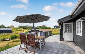 Relax on the outdoor deck with a shaded table and chairs, surrounded by charming countryside homes.
