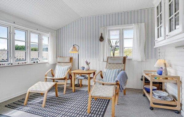 Relax in this inviting room with a high ceiling, comfortable seating area, and large windows.