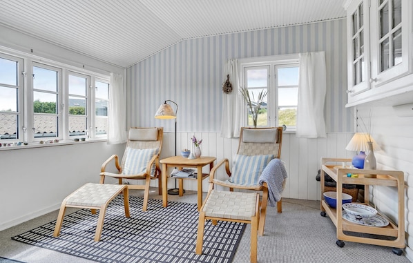Relax in this inviting room with a high ceiling, comfortable seating area, and large windows.