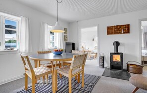 Enjoy meals around the central dining table, surrounded by comfortable seating and a warm fire from the wood-burning stove.