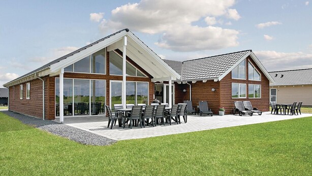 Une maison moderne dotée d’un grand patio, de grandes fenêtres et d’un espace extérieur aménagé et couvert.