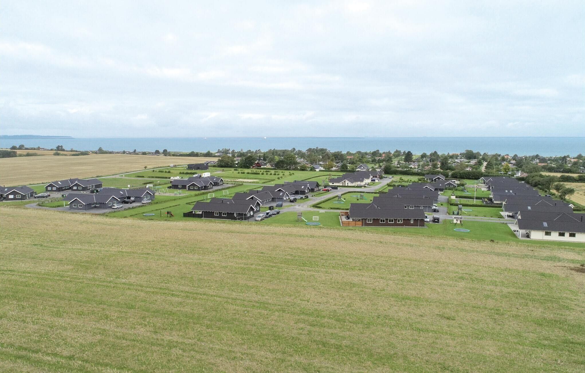 Un quartier résidentiel où les maisons sont alignées en rangées, avec de vastes pelouses verdoyantes et une vue sur la mer.