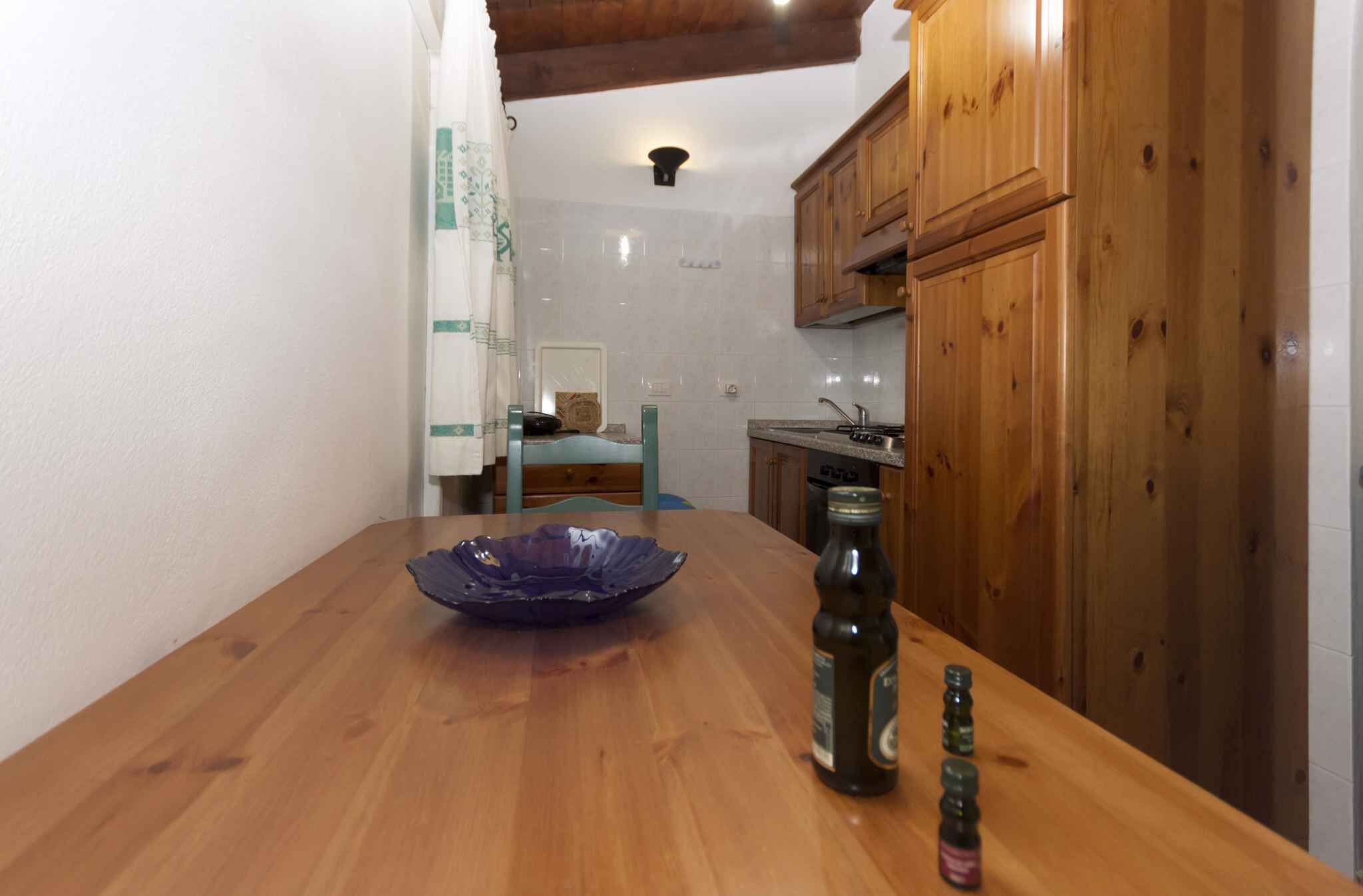 Une table de salle à manger en bois, avec un saladier bleu et des bouteilles de bière.