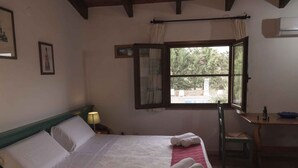 A hotel room with a bed, a window with curtains, a table with a chair, and a lamp. - Studio with swimming pool and air conditioning (Alghero)