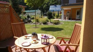 An outdoor patio with a round table, chairs, and a coffee pot.