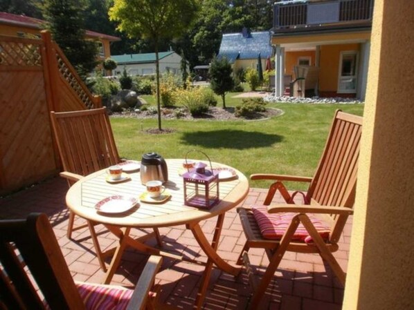 An outdoor patio with a round table, chairs, and a coffee pot.