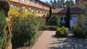 A courtyard with a statue, a pathway, and a building with multiple windows and balconies.