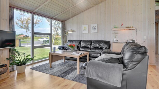 Ein modernes Wohnzimmer mit einer Ledersofa, einem Holztisch und einem Fernseher.